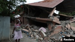 A woman walks past a school in Gros Morne, which was damaged in an earthquake that hit northern Haiti, Oct. 8, 2018.