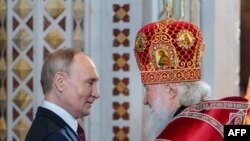Оваа фотографија направена и објавена од прес-службата на Руската православна црква на 5 мај 2024 година ги прикажува рускиот претседател Владимир Путин (лево) и рускиот православен патријарх Кирил (десно) како присуствуваат на православната велигденска служба.