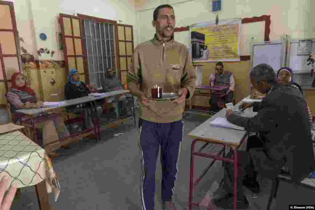 A worker serves other workers in a quiet polling station in central Cairo, March 27, 2018. 