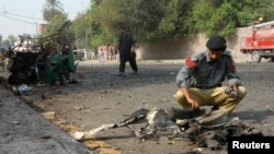 Seorang polisi tengah mengumpulkan barang bukti di tempat ledakan bon bunch dire di dekat sebuah konvoi Frontier Corps (FC) di Peshawar (23/9).
