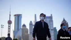 戴着口罩的行人行走在上海陆家嘴金融区的街道上。（2020年3月19日）