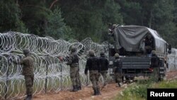 FILE - Polish soldiers build a fence on the border between Poland and Belarus near the village of Nomiki, Poland, August 26, 2021. 