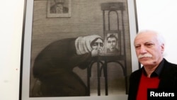 Syrian artist Youssef Abdelke stands near his artwork during an exhibition at a gallery in Beirut, Jan. 6, 2014. 