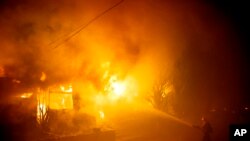 A firefighters hoses down flames as a home burns in the Getty fire area along Tigertail Road in Los Angeles, California, Oct. 28, 2019.