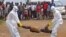 Health workers places the body of a man, inside a plastic body bag as he is suspected of dying due to the Ebola virus as people, rear, look on in Monrovia, Liberia, Thursday, Sept. 4, 2014. (AP Photo/Abbas Dulleh)