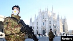FILE - Military officers wearing face masks stand outside Duomo cathedral, closed by authorities due to a coronavirus outbreak, in Milan, Italy, Feb. 24, 2020.