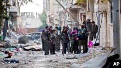 FILE - Fighters from Kurdish popular defense units gather during a short break before heading out to fight for new positions in Kobani, Syria.
