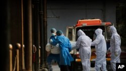 Health workers and relatives carry the body of a COVID-19 victim for cremation in New Delhi, India, Nov. 19, 2020.