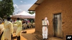 Un employé de l'Organisation mondiale de la santé décontamine l'entrée d'une maison située dans une parcelle où deux cas d'Ebola ont été découverts, dans le village de Mabalako, dans l'est du Congo, le 17 juin 2019.