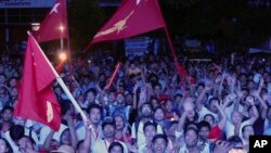 Pendukung pemimpin opposes Aung San Suu Kyi yang merupakan pemimpin Liga Nasional untuk Demokrasi Myanmar bersorak menyaksikan hasil penghitungan pemilu di layar LED di luar markas partai tersebut, 8 November 2015, di Yangon, Myanmar. (AP Photo/Khin Maung Win)
