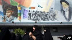 Iranian female worshippers join a rally after their Friday prayers to condemn Saudi-led airstrikes against Yemen, under a mural of the late Iranian revolutionary founder Ayatollah Khomeini and Basij paramilitary force, in Tehran, April 3, 2015.