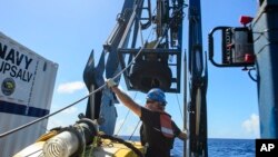 FILE - Tucker Bailey guides a towline through the A-frame while deploying the tow pinger aboard USNS Apache, Oct. 24, 2015. 