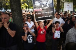 A woman holds up a banner saying ' Their life does not belong to us' during a demonstration against the wildfires in the Amazon outside the Brazilian embassy in Paris, Aug. 23, 2019.