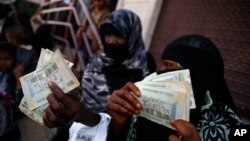FILE - Women display paper currency after they received it from the U.N. children's agency in Sanaa, Yemen, Nov. 14, 2015. 