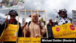 People dressed in costumes take part in a demonstration against the Transatlantic Trade and Investment Partnership (TTIP), a proposed free trade agreement between the European Union and the United States, in Munich April 18, 2015. The posters (L-R) read: 