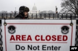 Pristalica novoizabranog predsjednika SAD-a Donalda Trumpa prolazi pored sigurnosne barikade u blizini američkog Capitola u Washingtonu dan prije Trumpove inauguracije. (Foto: ANDREW CABALLERO-REYNOLDS/AFP)
