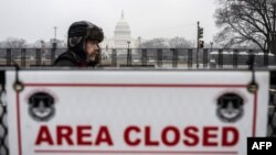 A supporter of US President-elect Donald Trump walks past a security barricade near the US Capitol in Washington, DC, on January 19, 2025, one day ahead of Trump's inauguration. (Photo by ANDREW CABALLERO-REYNOLDS / AFP)
