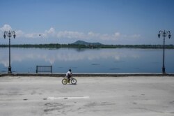 A boy rides a bicycle along the bank of the Dal Lake during a government-imposed nationwide lockdown as a preventive measure against the COVID-19 coronavirus, in Srinagar on April 23, 2020.