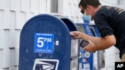Čovek ubacuje poštu u sanduče, Los Anđeles, 17. avgust 2020. (Foto: AP/Damian Dovarganes)