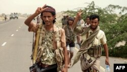 Yemeni pro-government forces flash the victory gesture as they arrive in al-Durayhimi district, about 9 kilometers south of Hodeidah international airport, June 13, 2018.