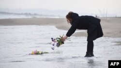 FILE - A woman puts flowers into the sea to pray for victims of the 2011 earthquake and tsunami in Sendai, northern Japan on the anniversary of the event. (AFP / TORU YAMANAKA)