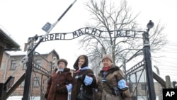 FILE - Holocaust survivors walk outside the gate of the Auschwitz Nazi death camp in Oswiecim, Poland, Jan. 27, 2015. 