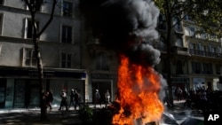 People walk past a burning barricade during a climate demonstration, in Paris, Sept. 21, 2019. 
