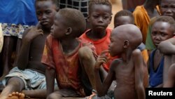 Anak-anak yatim piatu dan yang terpisah dari orang tua mereka di Kadugli berkumpul untuk makan daun rebus di Kamp Pengungsi di wilayah yang dikuasai Gerakan Pembebasan Rakyat Sudan-Utara (SPLM-N) di Pegunungan Nuba, Kordofan Selatan, Sudan, 22 Juni 2024. (Thomas Mukoya/REUTERS)