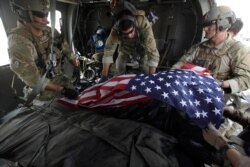 FILE - Upon landing after a helicopter rescue mission, Tech. Sgt. Jeff Hedglin, right, an Air Force Pararescueman, or PJ, drapes an American flag over the remains of the first of two U.S. soldiers killed minutes earlier in an IED attack.