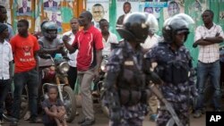 FILE - Ugandan riot police stand close to dejected opposition supporters to prevent them from demonstrating, shortly after the election result was announced, in downtown Kampala, Uganda, Feb. 20, 2016. 