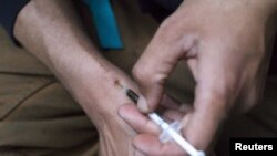 FILE - A man injects himself with heroin using a needle obtained from the People's Harm Reduction Alliance, the nation's largest needle-exchange program, in Seattle, Washington. 