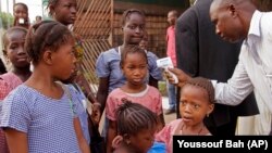 Children in Conakry, Guinea, return to school - and a daily temperature check.