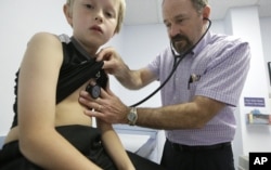 Dr. John Porter examines Connor Russell, 8, during an office visit Tuesday, March 31, 2015, in Richardson, Texas. (AP Photo/LM Otero)