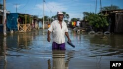 FILE - A local resident wades through water on a street in the "El Indio" settlement on the outskirts of Piura, in northern Peru, March 23, 2017.