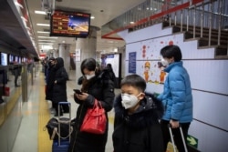 Passengers wear face masks as they wait for a train at a subway station in Beijing, Jan. 24, 2020.