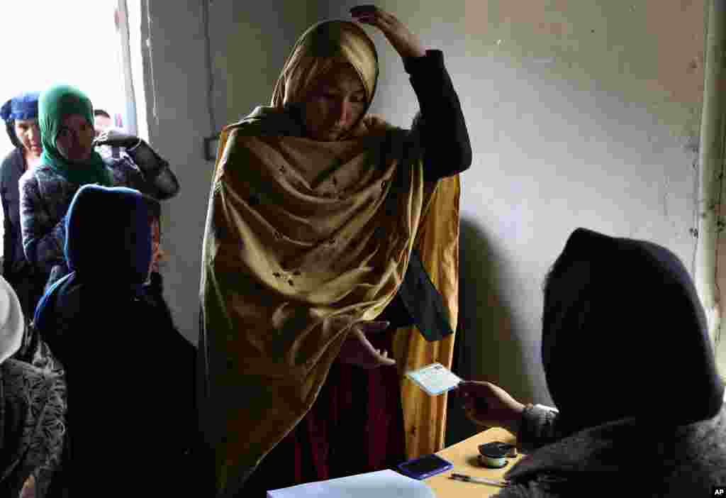 Seorang perempuan Afghanistan menerima kartu suara dari panitia pemilu di Kabul.