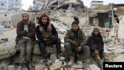 Rebel fighters sit on the rubble of damaged buildings as they wait to be evacuated from a rebel-held sector of eastern Aleppo, Syria Dec. 16, 2016.