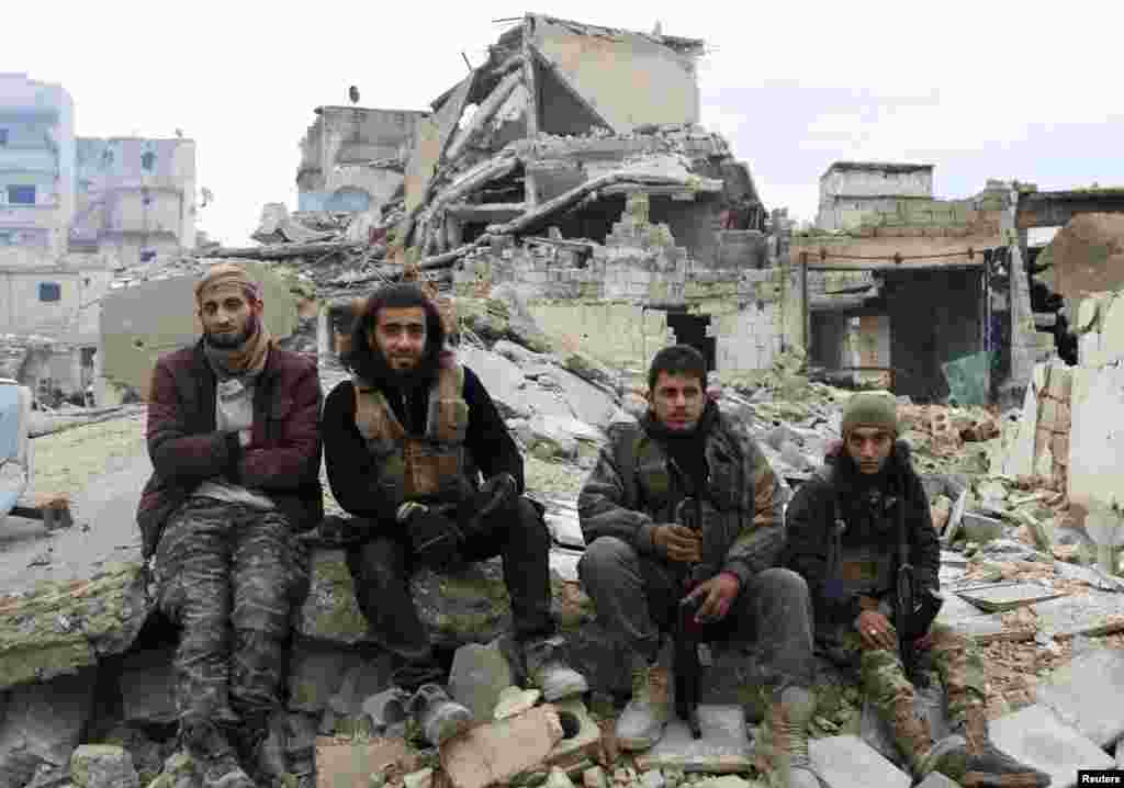 Rebel fighters sit on the rubble of damaged buildings as they wait to be evacuated from a rebel-held sector of eastern Aleppo, Syria Dec. 16, 2016.