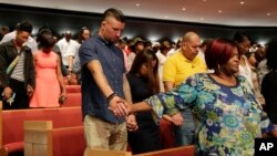 Church goers join hands as they take part in a service at the Potter's House, Sunday, July 10, 2016, in Dallas, that included a memorial to five police officers killed last week in Dallas as well as a town hall meeting discuss recent police shootings. (AP Photo/Eric Gay)
