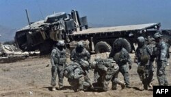 Binh sĩ NATO trợ giúp một đồng đội bị thương trong vụ nổ bom vệ đường ở Kandahar, miền nam Afghanistan, ngày 12/10/2010. Một vụ nổ trên một máy bay trực thăng đã giết chết 1 người và làm bị thương 8 người khác ngay sau hạ cánh tại một căn cứ ở tỉnh Kunar