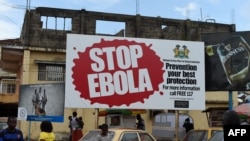 FILE - People walking past a billboard reading "Stop Ebola" in Freetown, Sierra Leone, Nov. 7, 2014. 