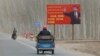 FILE - China's Xi Jinping is seen on a billboard with the slogan, "Administer Xinjiang according to law, unite and stabilize the territory, culturally moisturize the territory, enrich the people and rejuvenate the territory," in Xinjiang Uyghur Autonomous Region, March 21, 2021. 