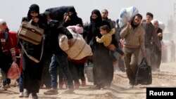 People walk with their belongings as they flee the rebel-held town of Hammouriyeh, eastern Ghouta, Syria, March 15, 2018.
