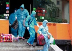 People walk toward an ambulance to be driven to a hospital for quarantine relating to a suspected COVID-19 case in Hanoi, Vietnam, July 29, 2020.