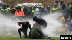 Police uses a water canon during a protest against restrictions put in place to curb the spread of the coronavirus disease (COVID-19), in Amsterdam, Netherlands January 24, 2021. REUTERS/Eva Plevier