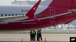 Anggota kru berbincang dekat pesawat Boeing 737 MAX 8 yang dioperasikan Shanghai Airlines di landasan Bandara Hongqiao di Shanghai, China, 12 Maret 2019. 