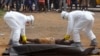 FILE - Health workers place the body of a man, whom they suspect of dying of the Ebola virus, inside a plastic body bag as a small crowd watches in Monrovia, Liberia, Sept. 4, 2014. 