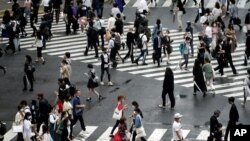People walk on pedestrian crossings, July 17, 2020, at Tokyo's Shibuya district