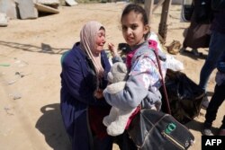 A woman who fled the al-Shifa hospital and its vicinity in Gaza City reacts as she sits amid some of her belongings in central Gaza on March 21, 2024.