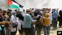Palestinian protesters evacuate a wounded youth near the Israeli border fence, east of Khan Younis, in the Gaza Strip, May 14, 2018. 